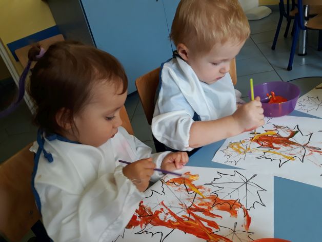 Dzieci farbami malują jesienne liście